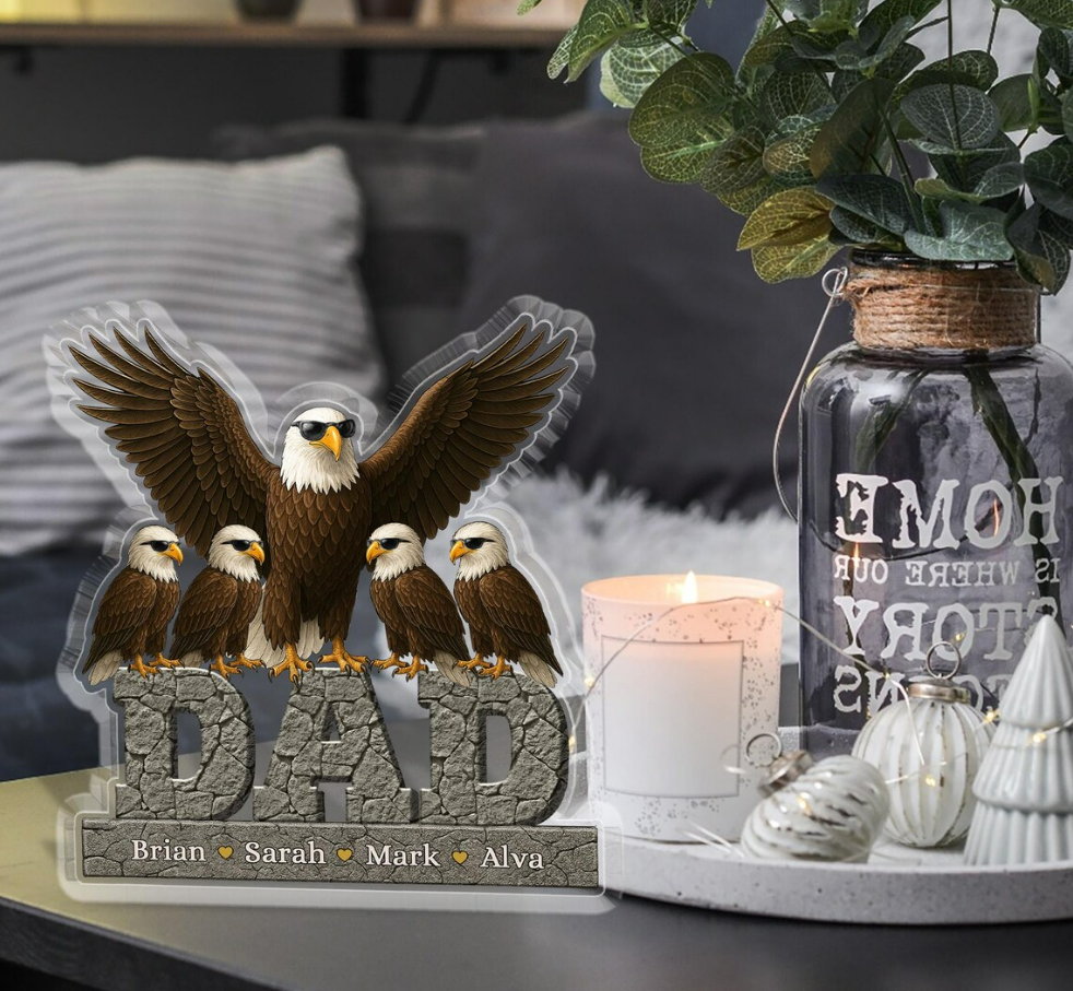 Decorative eagle sculpture with 'DAD' and names on a table with a candle and plant.