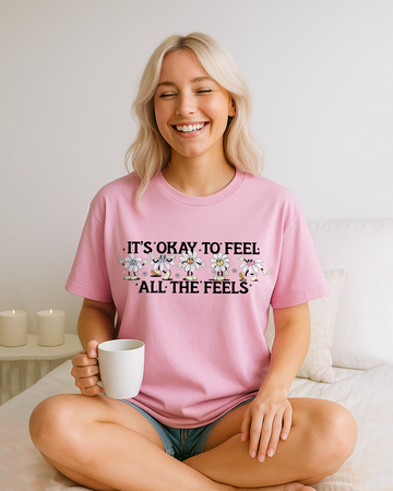 Blossom pink Comfort Colors shirt with playful daisy character design and “It’s Okay To Feel All The Feels” quote