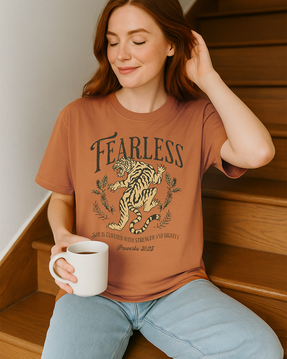 Yam Comfort Colors tee with “She is clothed with strength and dignity” verse and bold tiger graphic. Worn in soft, natural setting.