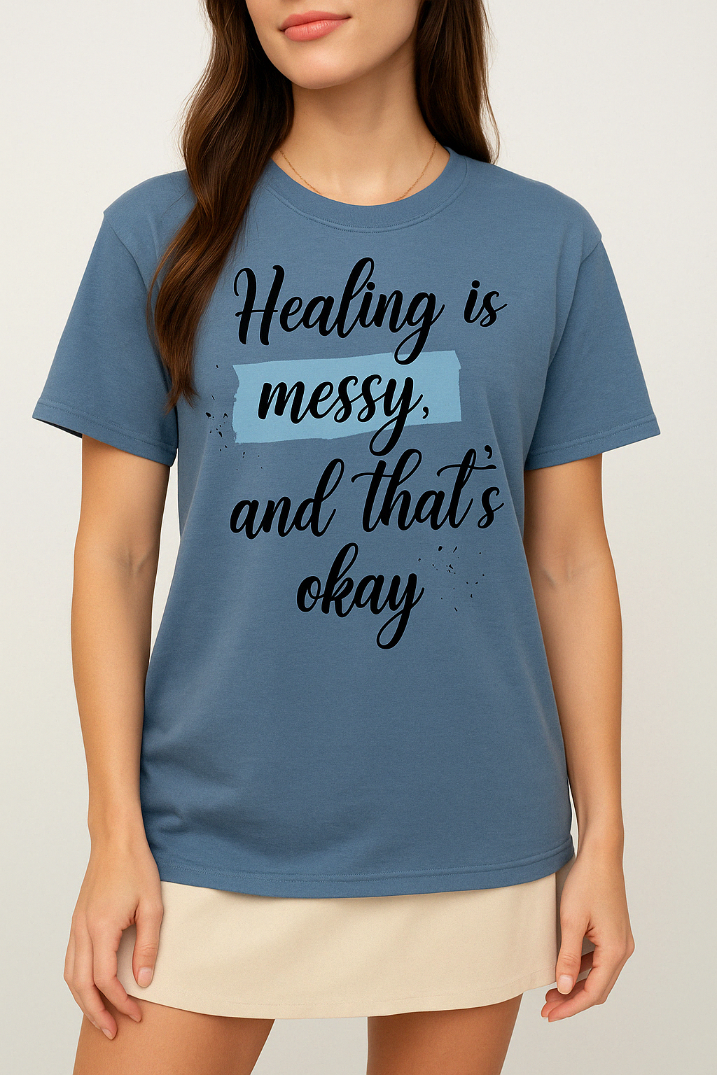 Pink Comfort Colors t-shirt with “Healing is messy and that’s okay” quote. Mental health tee worn by woman with gold accessories.