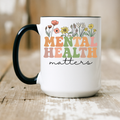 Mental Health Matters two-tone ceramic mug with floral design placed on wooden table. 15oz size.