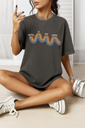 Pepper Comfort Colors t-shirt with rainbow “Healing is not linear” quote. Worn by woman sitting cross-legged indoors.
