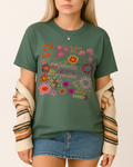 Earth-toned moss green shirt worn with denim; bold floral design and quote promote mental wellness.