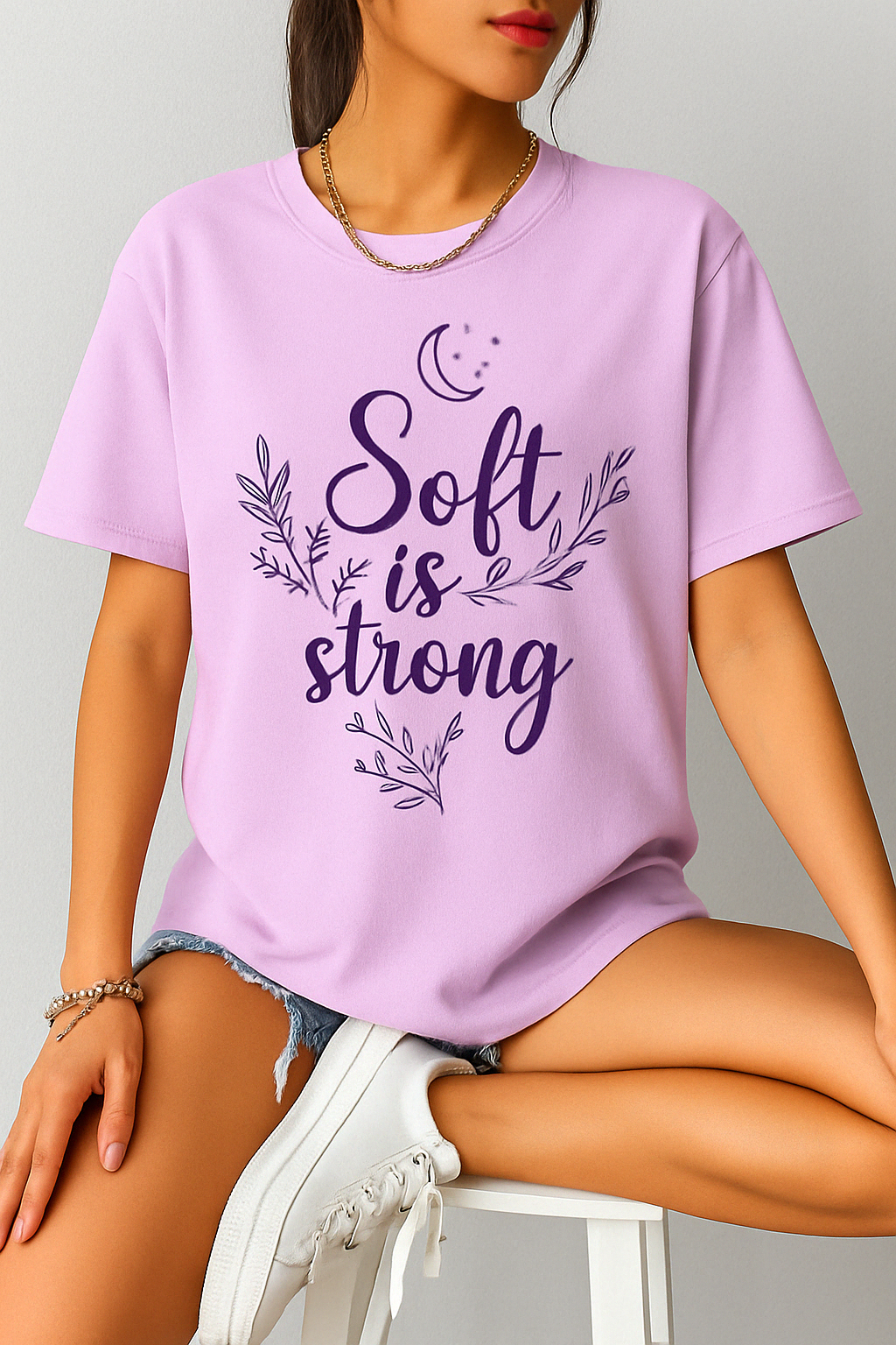 Orchid lavender Comfort Colors 1717 shirt with “Soft is Strong” design, worn by woman sitting with white sneakers and pastel styling.