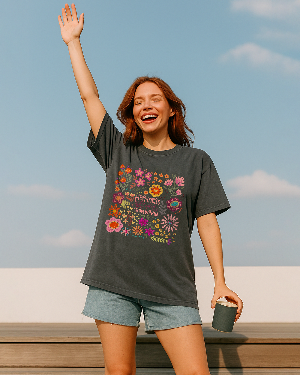 Woman wearing a Comfort Colors 1717 shirt in Pepper with floral “Happiness Blooms From Within” design; earthy tones with a cozy vintage vibe.