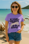 Violet Comfort Colors tee with Joshua 1:9 quote and leaping tiger artwork. Worn at the beach with bold joyful vibe.