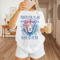Woman in a bright white Jesus shirt, holding iced coffee, with vibrant lion face and scripture text “Greater is He” – cozy Christian morning outfit.