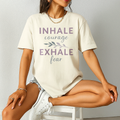Ivory Comfort Colors tee with self-care quote “Inhale Courage, Exhale Fear” in purple tones. Styled with boots and cozy vibes.