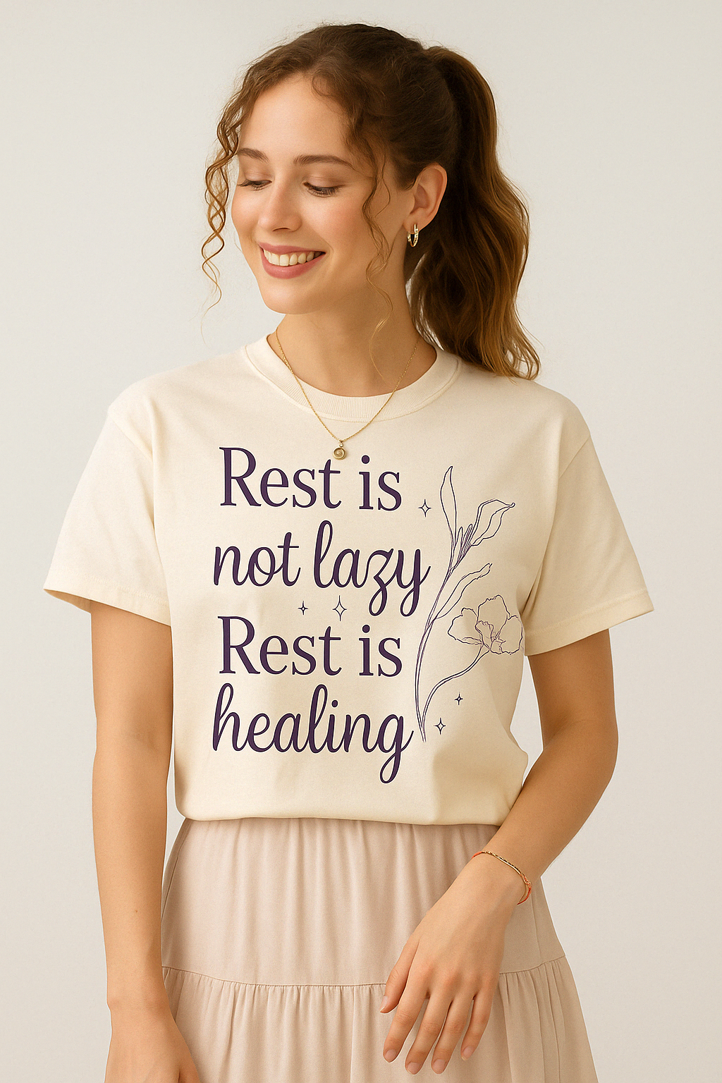 Ivory Comfort Colors t-shirt with handwritten “Rest is not lazy. Rest is healing” quote, worn by woman with curled ponytail and light skirt.