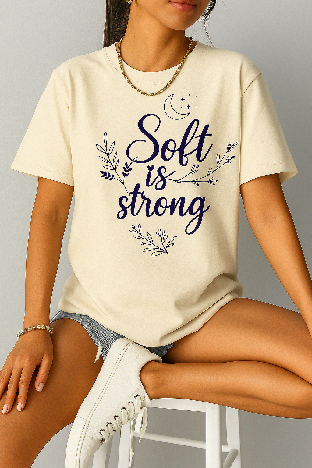 Ivory Comfort Colors 1717 t-shirt with “Soft is Strong” quote, worn by woman seated casually in a soft-lit setting.